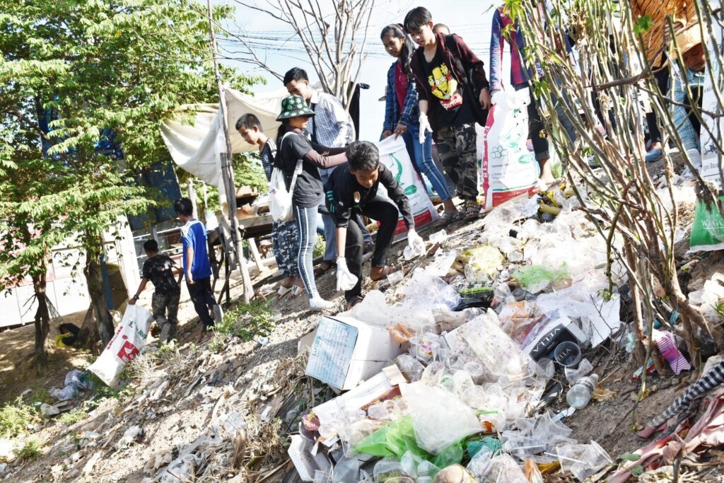 Volunteers collect plastic from a bank covered in waste
