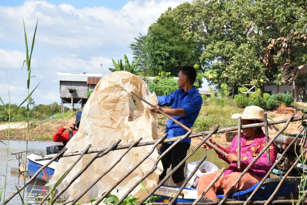 Volunteers in a boat lift a large bag of plastic
