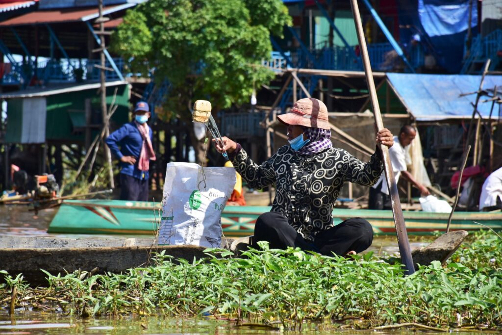 Villagers hand bags of plastic across boats