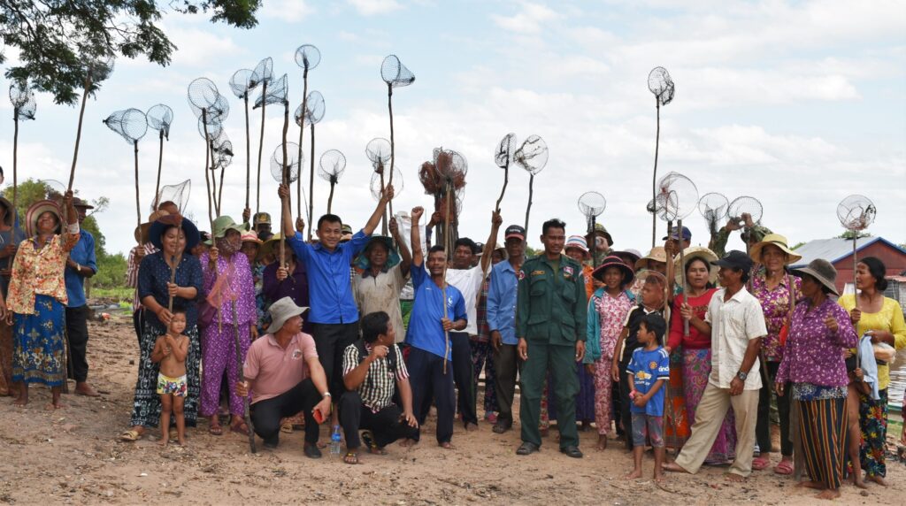 Villagers raise fishing nets in the air after a clean-up