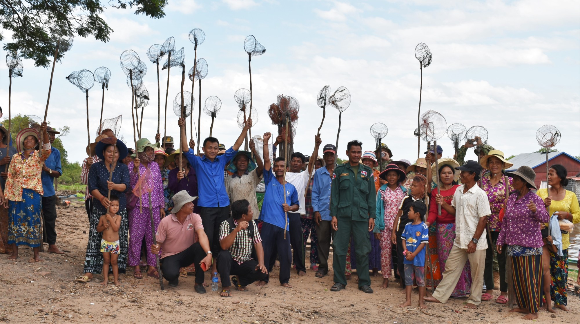 Villagers raise fishing nets in the air after a clean-up