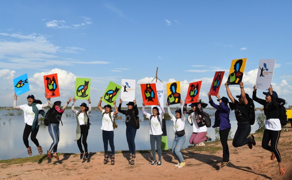 Young people jump holding hand-painted posters about plastic