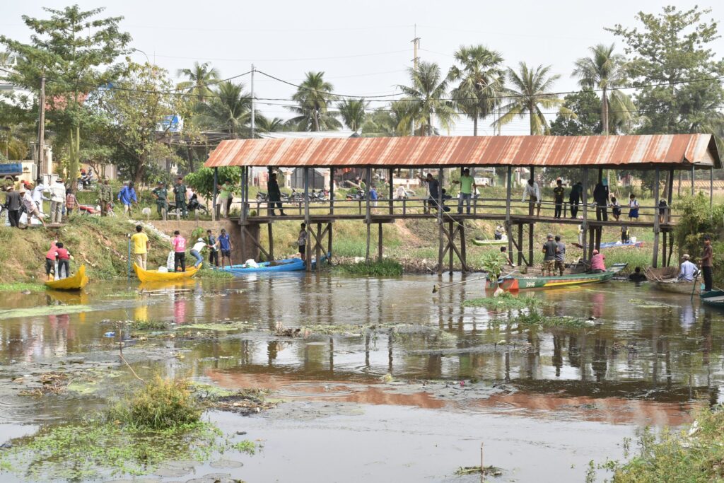 Small boats gather under a wooden walkway during a clean-up