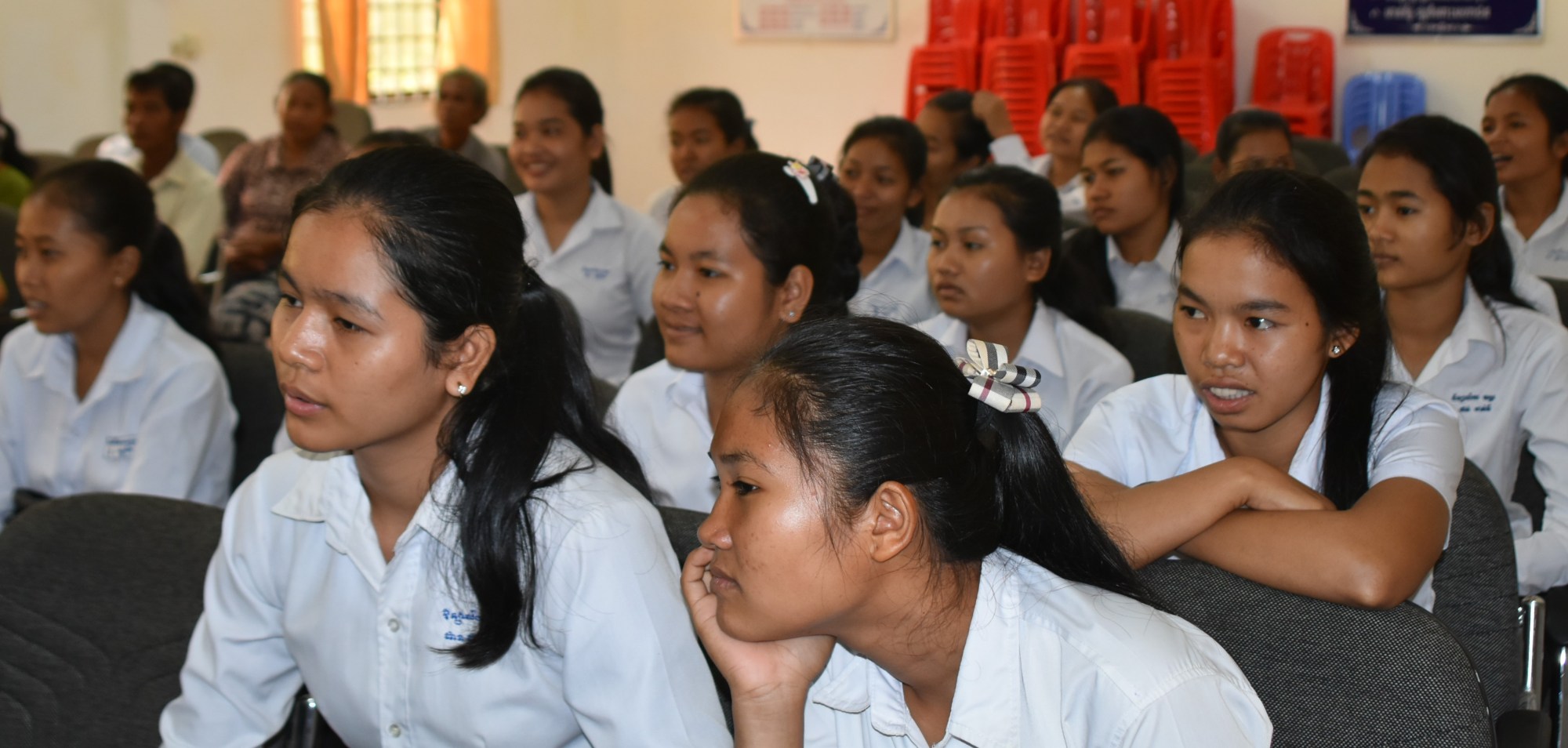 Students in white shirts listen during a workshop
