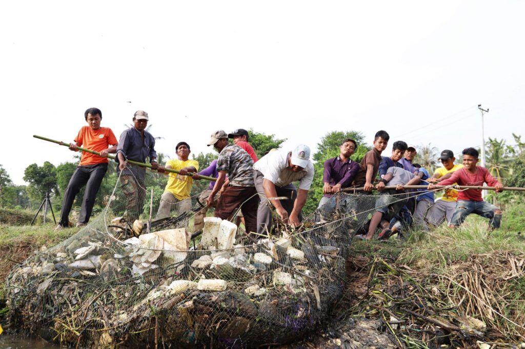 A group hauls a large net full of plastic onto the bank